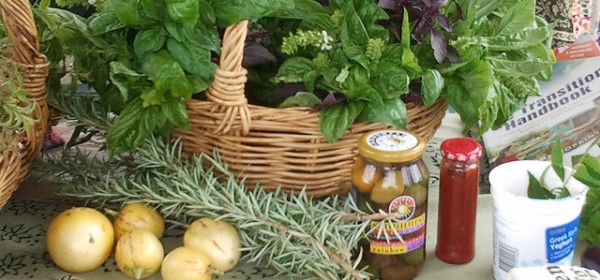 February Harvest - Sustainable Fawkner Food Produce Swap image by Takver (flickr) A basket of bunches of basil on a table with few fruit, sprigs of rosemary, and bottled goods in front of the basket.