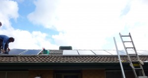 the first row of solar panels being installed on the roof