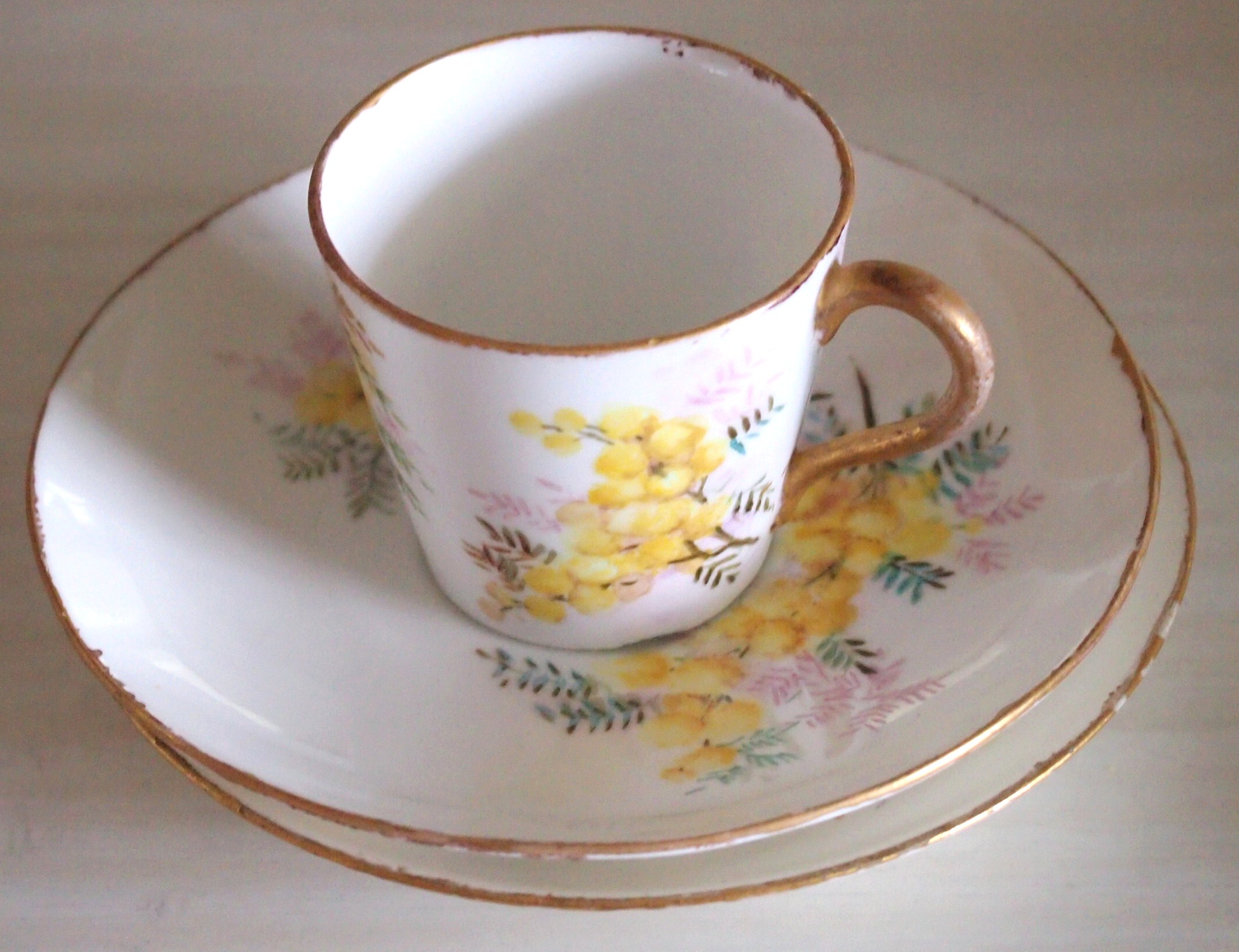 Small bone china tea cup with gold rim and yellow flower pattern on cup and saucer