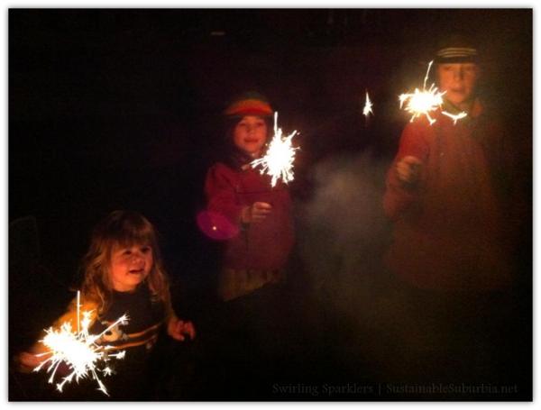 Three kids swirling sparklers in the dark