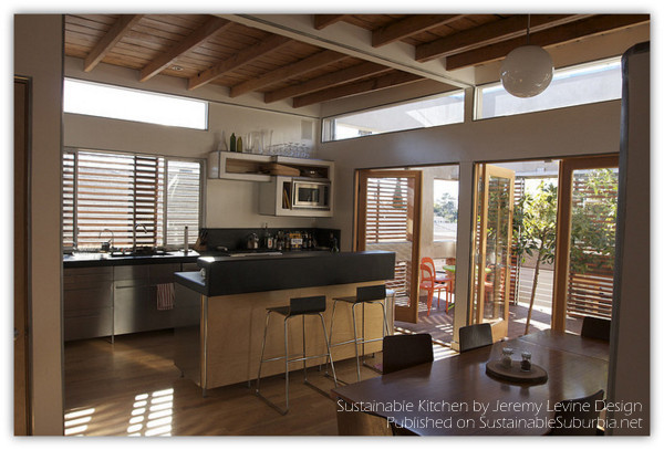 A gorgeous kitchen with countertops made with recycled coal fly ash and natural black pigment,  vaulted, recycled wood ceiling, and lots of natural light.