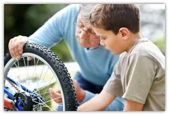 a child and his grandfather examine a bike wheel