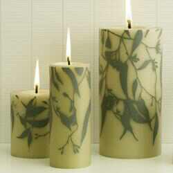 Three lit candles with a hand painted gum leaf design.