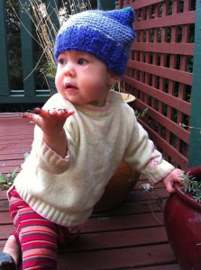 One year old Eliane modelling her square beany, and holding up for hand as if to say "what"?