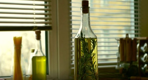 Attractive bottle of olive oil with several sprigs of rosemary inside. 