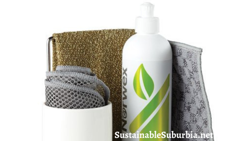 image shows a white tray with a bottle of norwex dishwashing liquid and a white ceramic cup on it. In the cup is a rolled up grey norwex mesh dish cloth.