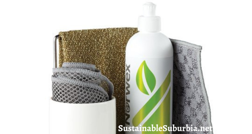 image shows a white tray with a bottle of norwex dishwashing liquid and a white ceramic cup on it. In the cup is a rolled up grey norwex mesh dish cloth.