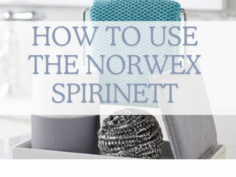 How to use the Norwex spirinett. Image shows stainless steel spirinett scrubby on the white porcelain sink organiser, with a turquoise kitchen cloth in the background.