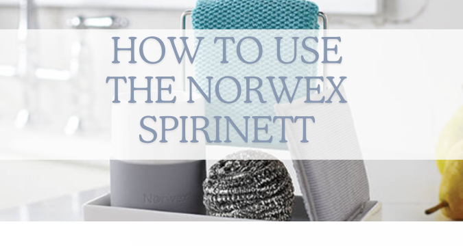 How to use the Norwex spirinett. Image shows stainless steel spirinett scrubby on the white porcelain sink organiser, with a turquoise kitchen cloth in the background.